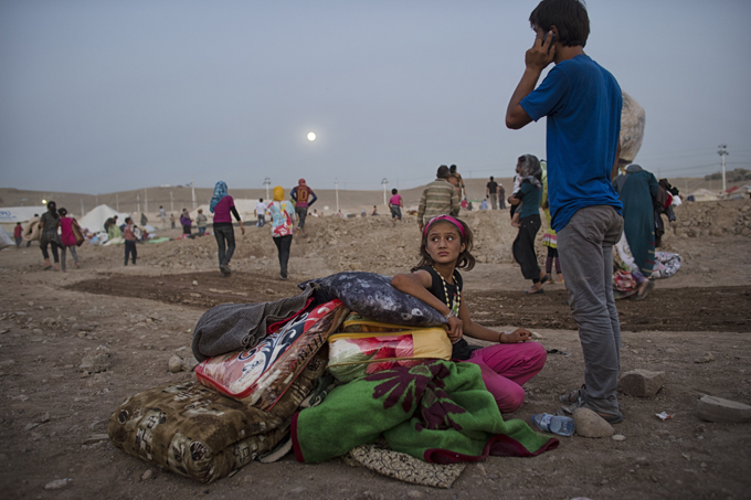 Syrian refugees wait for tents in the moonlight at the Karkos camp outside of Erbil, in northern Iraq. Photo by Lynsey Addario, August 20, 2013.